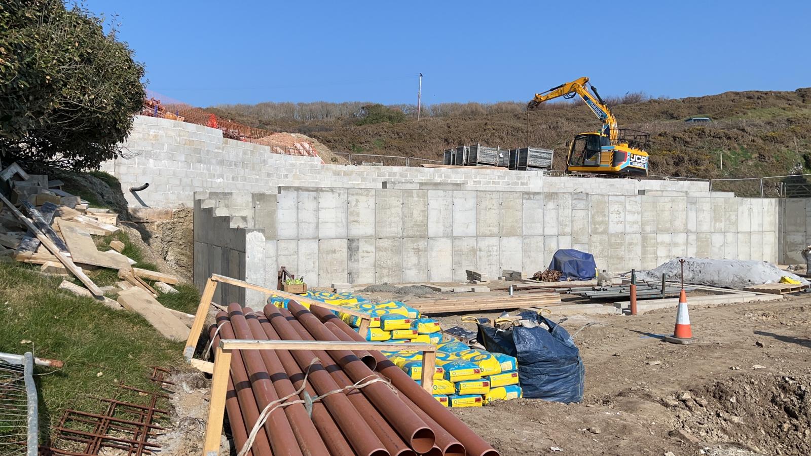 Land drainage pipes and cement bags staged in front of the concrete retaining walls at Porthleven