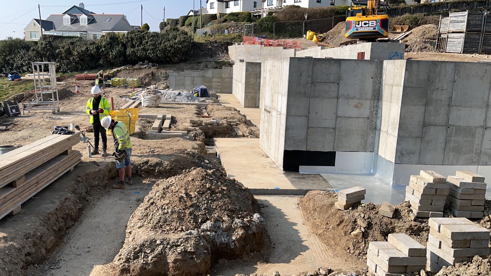 Operatives working beside a waterproofed reinforced concrete retaining wall at Porthleven
