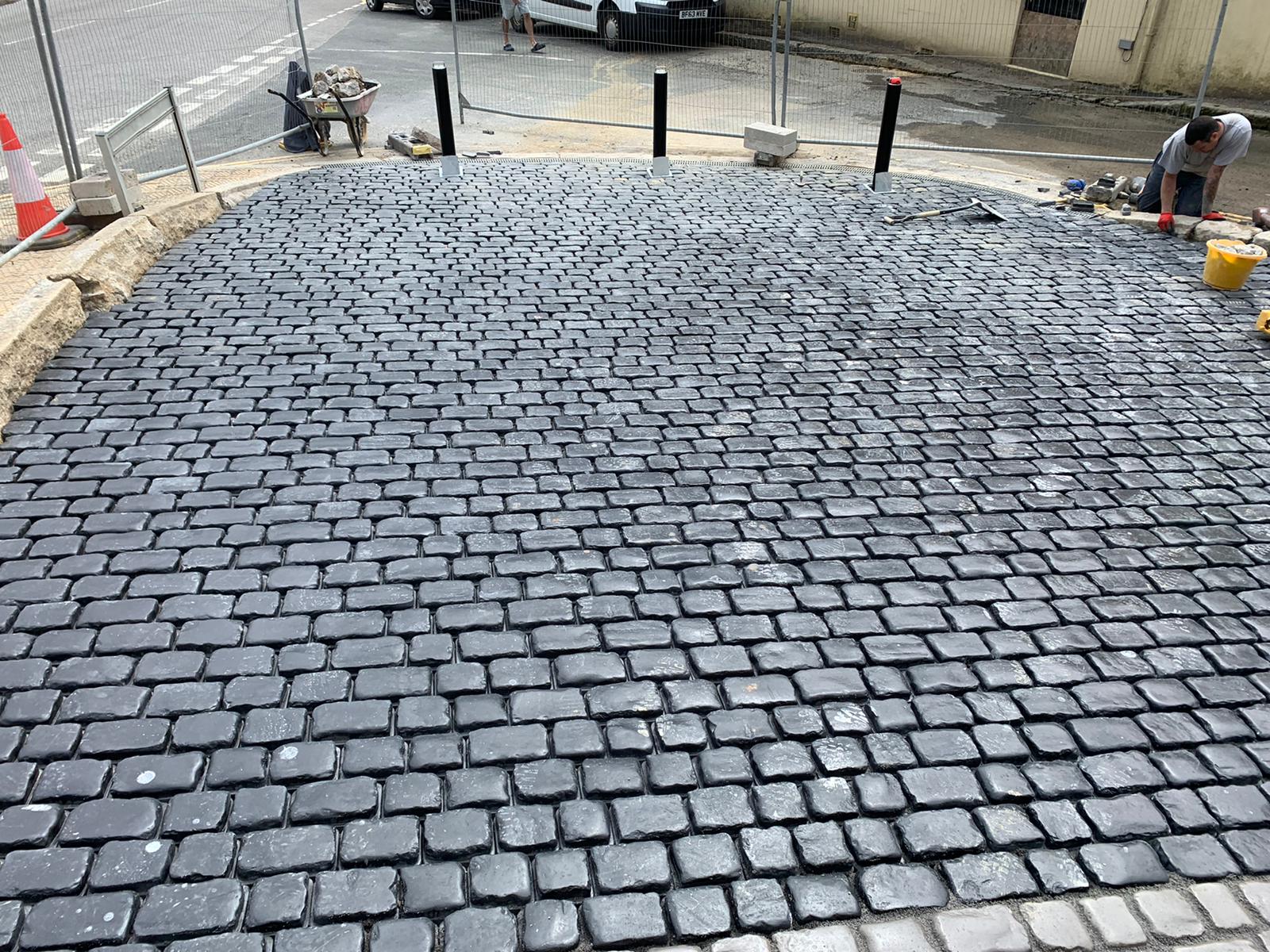Freshly laid Marshalls cobbles being finished by hand against the granite kerbing on Lannoweth Road, Penzance