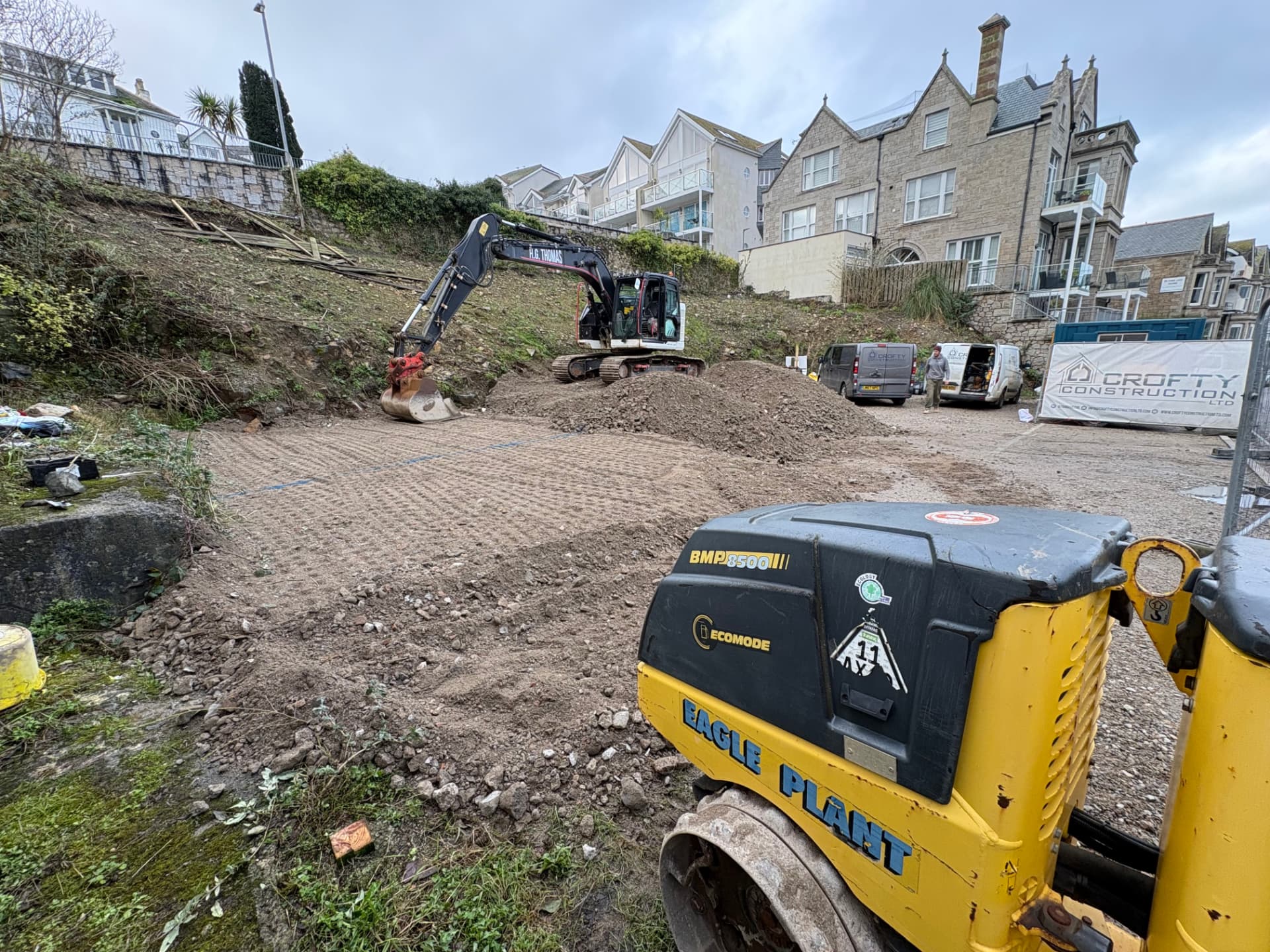 Compacted fill forming the lower platform area with excavator and roller on site at Elvan House